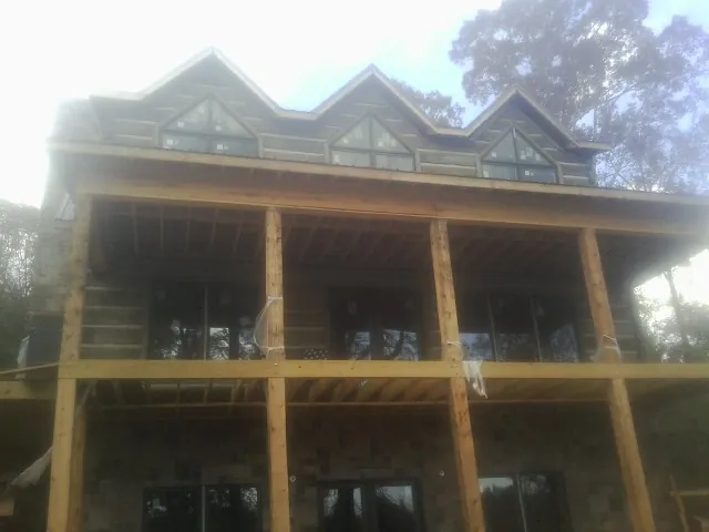 Dormers and porch framing on a large log home under construction — Roof Coating work by our crew in Schenley