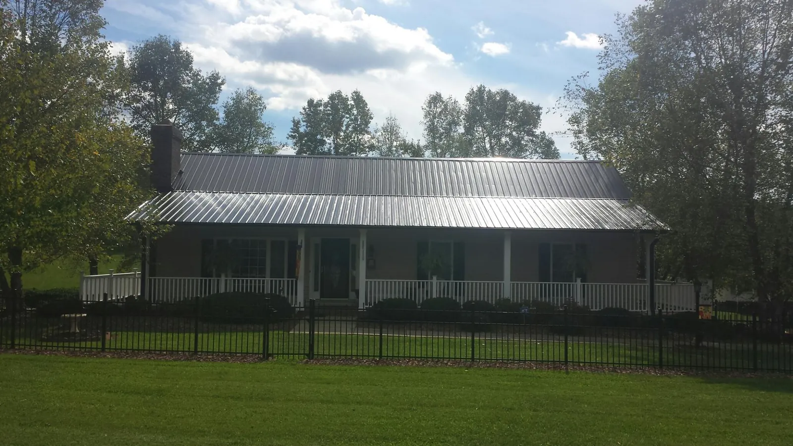 Gray metal roof on a brick ranch with a full width front porch — Gutter Guard Installation work by our crew in Schenley