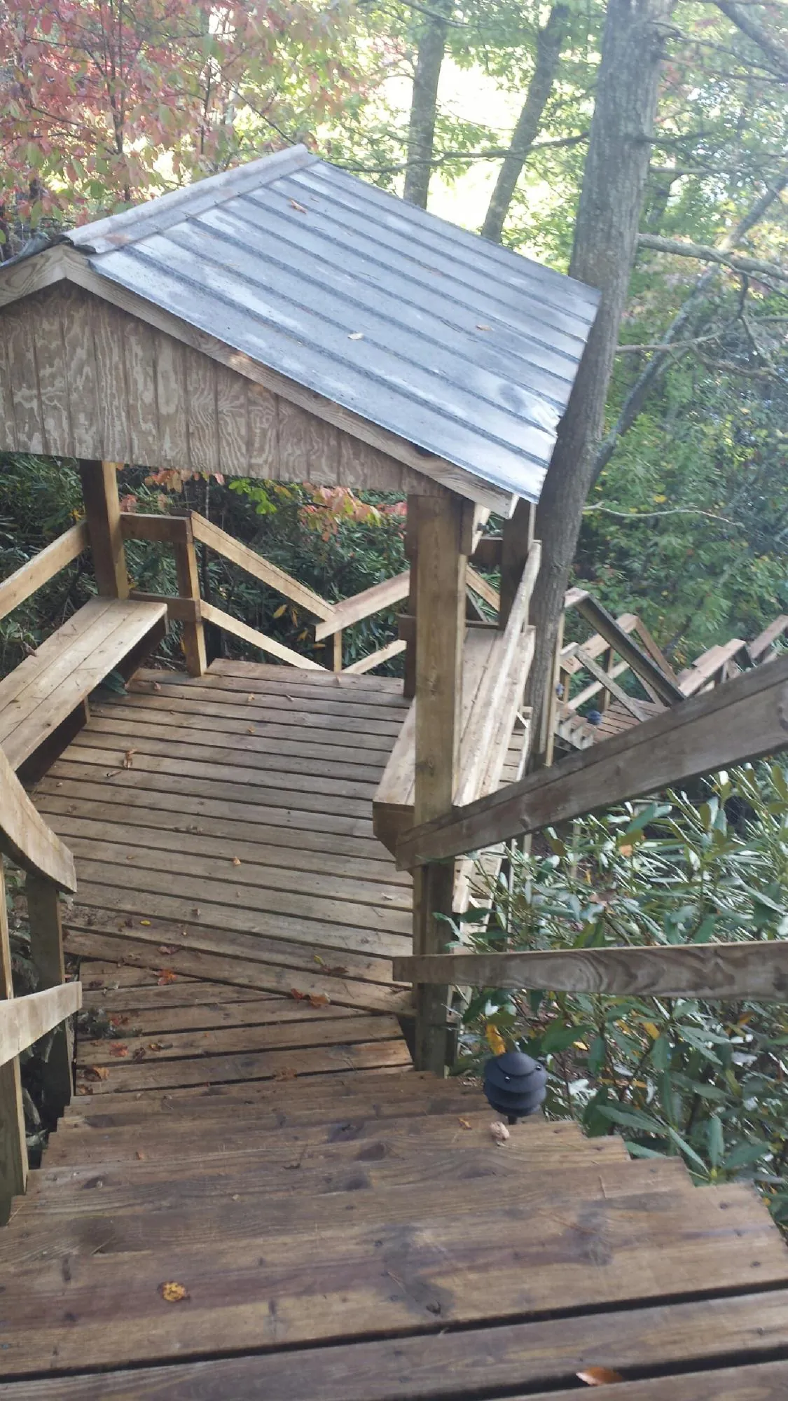 Metal roofed shelter over wooden steps on a wooded walkway — Skylight Repair & Installation work by our crew in Schenley