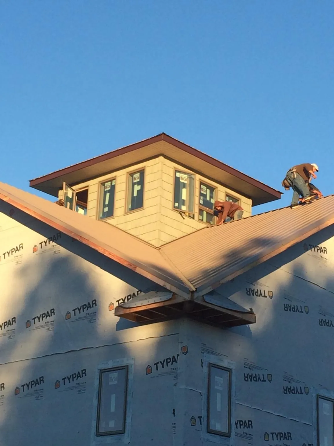 Roofers working around a rooftop cupola on a new metal roof at sunset — Roof Waterproofing in Schenley by Roofing Brothers